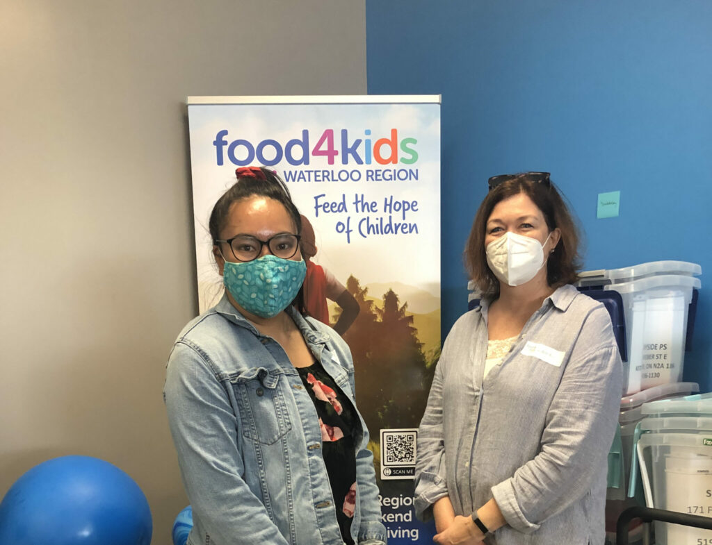 Two PPO Employees posing in front of Food4kids sign