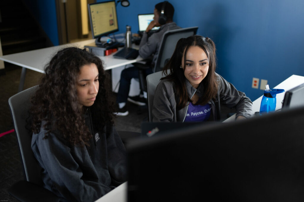 Two PPO employees looking at a screen, one working behind