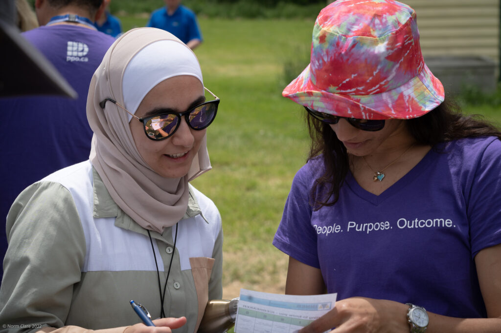 Two PPO employees looking at a piece of paper in sunglasses in a field