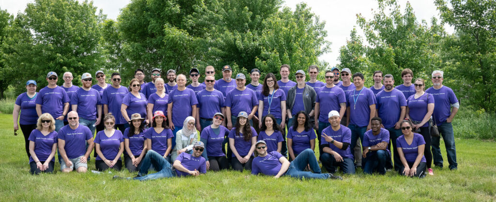 PPO Team in purple t-shirts smiling at camera in a field